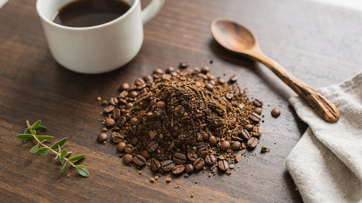 Coffee beans and grounds with a cup and spoon on a wooden table