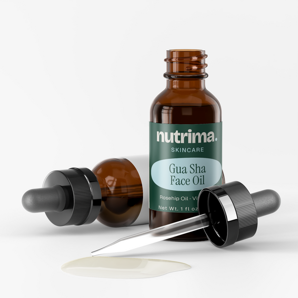 Amber bottles of Gua Sha Face Oil with dropper and oil pooled below, highlighting the skincare product by nutrima.
