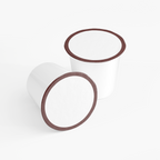 Two white coffee pods with brown rims, showcasing Rich Hazelnut Coffee Pods (Medium Roast) by nutrima.