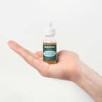 A hand holds a bottle of Dark Spot Serum for Normal Skin featuring a green label and dropper cap, by nutrima.