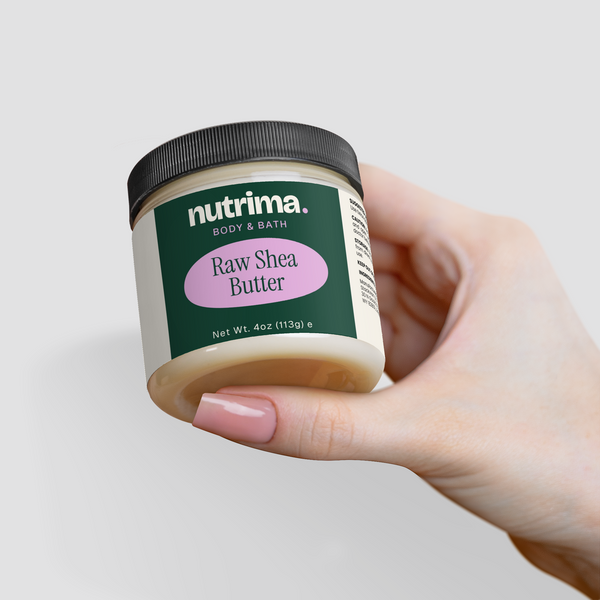 A hand holds a jar of Raw Shea Butter with a black lid and clear container, showcasing the product label by nutrima.