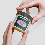 A jar of Raw Shea Butter by nutrima held between hands, showcasing its natural cream color and elegant packaging.