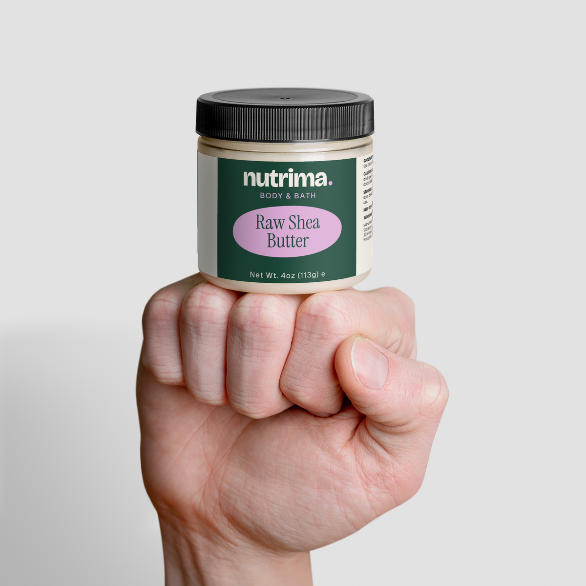A hand holds a jar of Raw Shea Butter, featuring a green label and black lid, by nutrima.