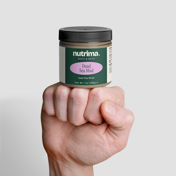 A hand holds a jar of Dead Sea Mud featuring a green label, showcasing the product by nutrima.