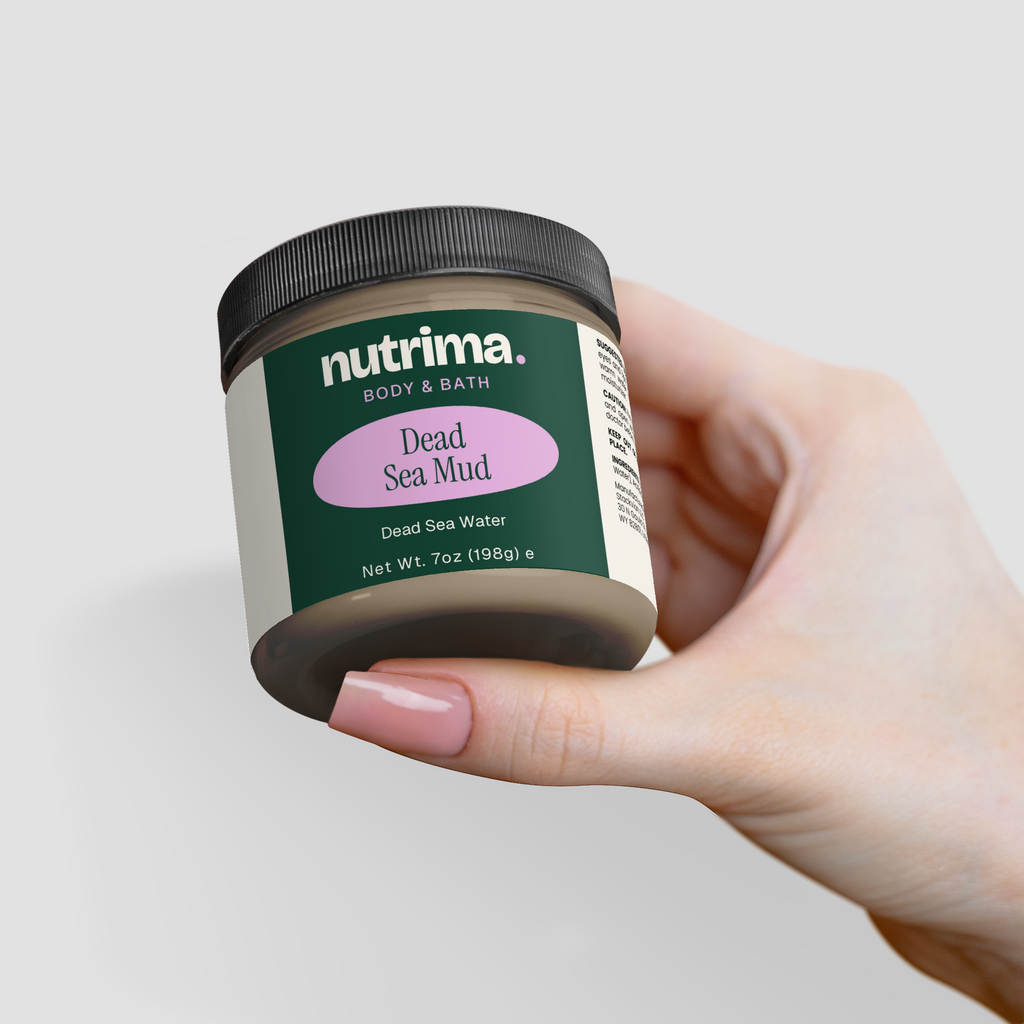 A hand holding a jar of Dead Sea Mud with a black lid and green label, showcasing the product by nutrima.