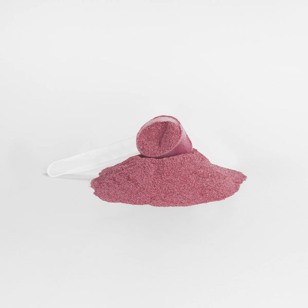 Vibrant pink Beetroot Powder in a clear scoop beside a mound, showcasing its fine texture. by nutrima.