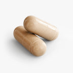 Two glossy, beige Mushroom Complex 10 X capsules are stacked together, showcasing their smooth texture by nutrima.