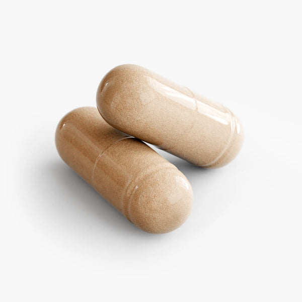 Two glossy, beige Mushroom Complex 10 X capsules are stacked together, showcasing their smooth texture by nutrima.
