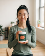 nutrima Creatine Monohydrate jar held by a woman in a home training room — AI-generated brand image