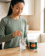 nutrima Creatine Monohydrate jar on a counter as a woman stirs powder into a glass of water — AI-generated brand image