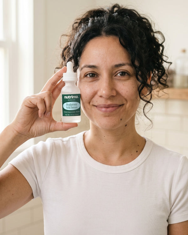 nutrima Hyaluronic Acid Serum dropper bottle held by a woman in a bathroom — AI-generated brand image