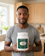 nutrima Plant Protein (Vanilla) tub held by a man in a home kitchen — AI-generated brand image