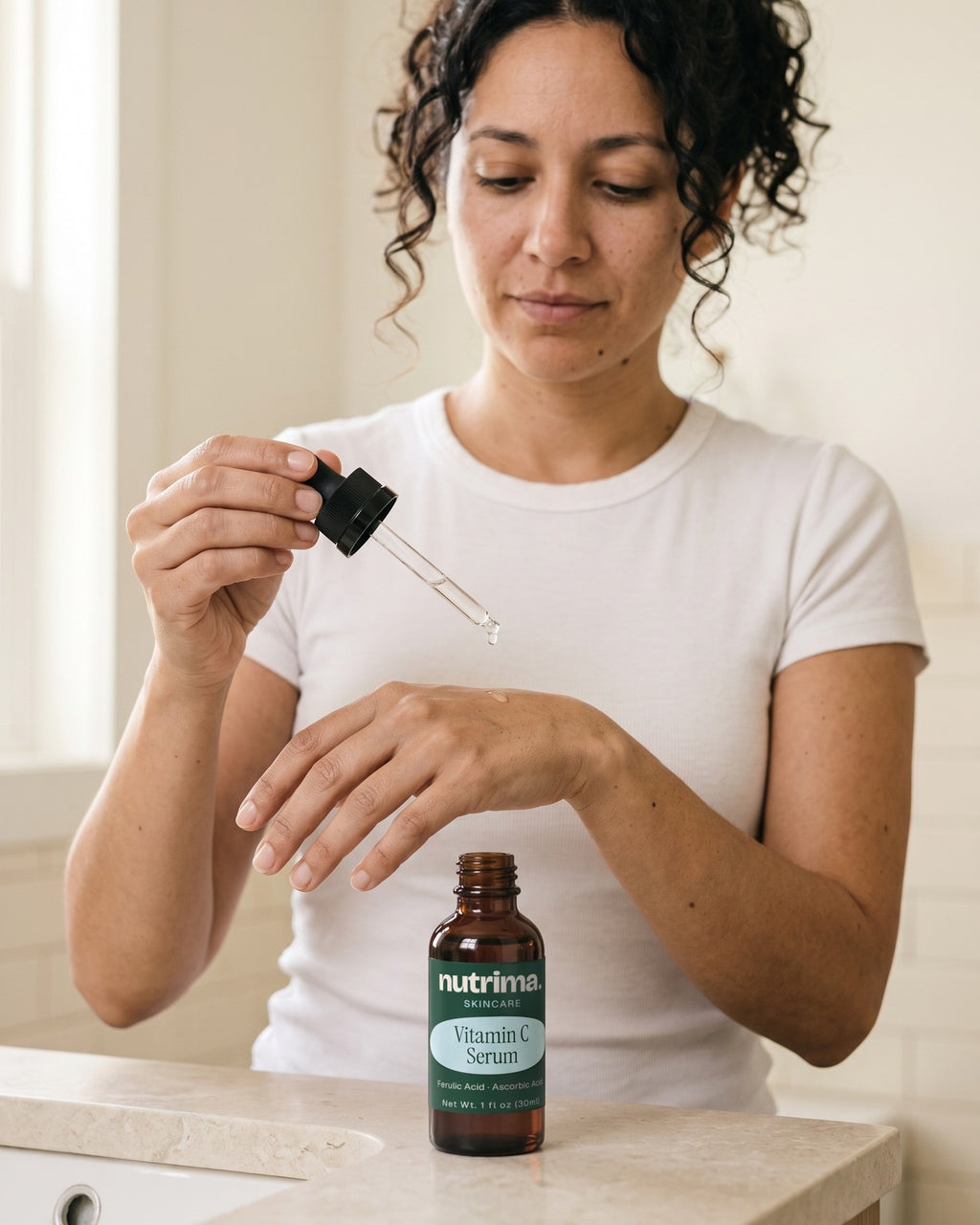 nutrima Vitamin C Serum bottle on a bathroom vanity as a woman holds the dropper over her hand — AI-generated brand image