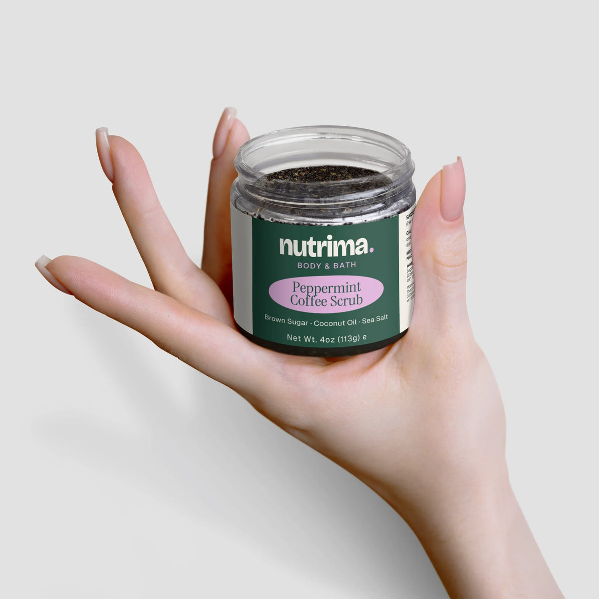 A hand holds the Peppermint Coffee Scrub jar, showcasing its unique blend of ingredients by nutrima.