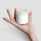 A hand holds a jar of creamy Recovery Cream with a blank label, showcasing the product's luxurious texture by nutrima.