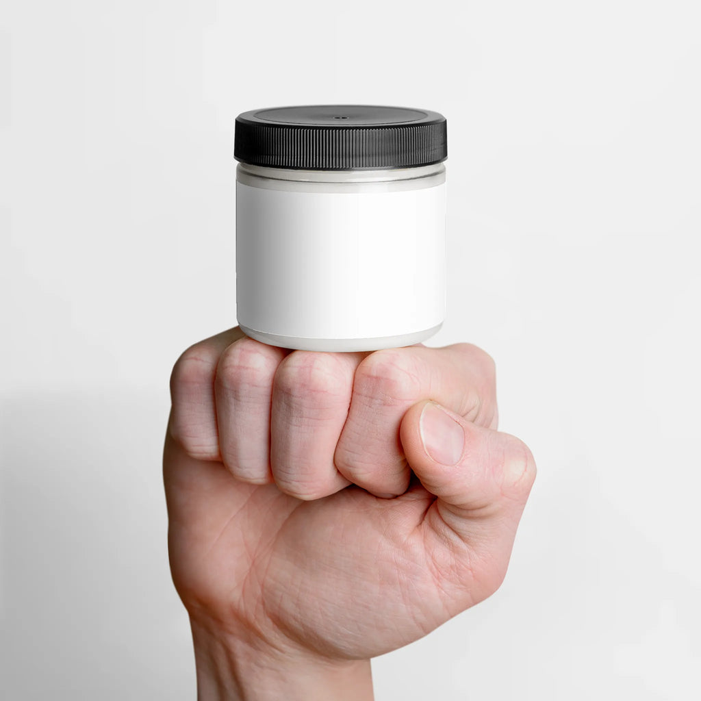 A hand holds a jar of Recovery Cream with a white label and black lid, showcasing the product's sleek design by nutrima.