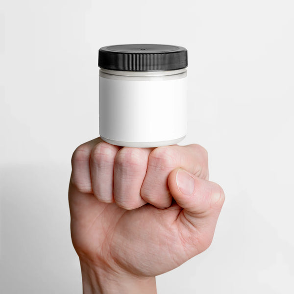 A hand holds a jar of Recovery Cream with a white label and black lid, showcasing the product's sleek design by nutrima.